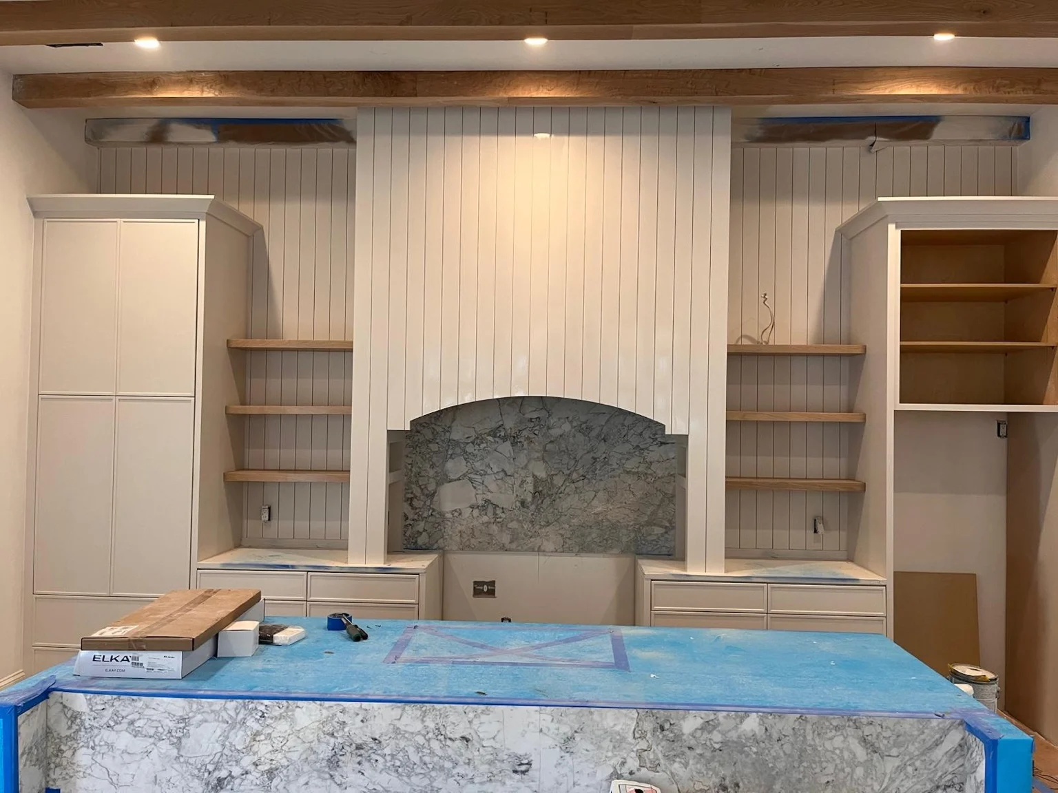 Original cabinetmaker project photograph showing white cabinetry, curved hood, oak shelves and stone island during installation