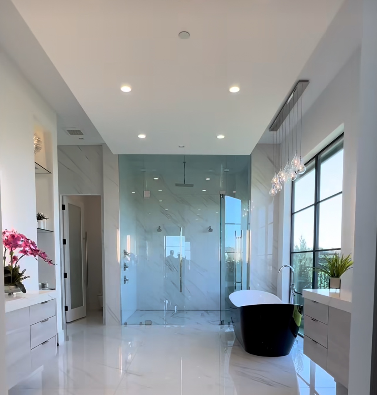 Glass shower and freestanding black bathtub