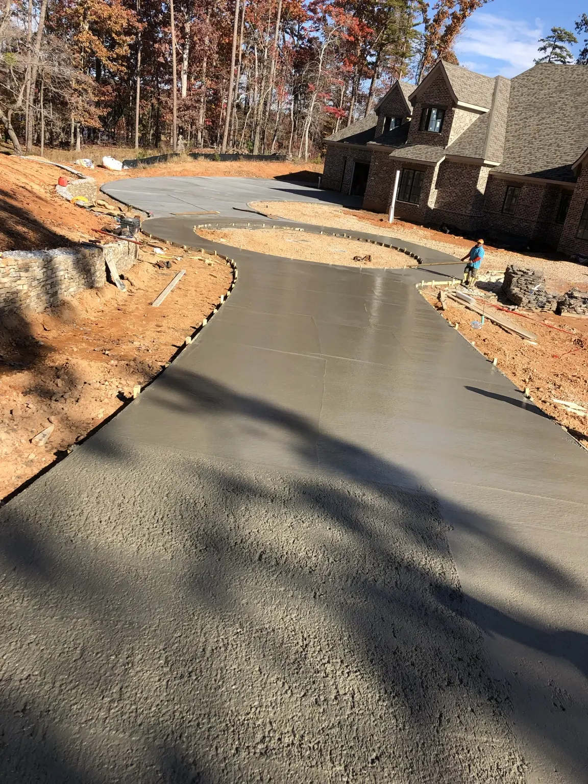 Freshly placed curved concrete driveway at a residential construction site