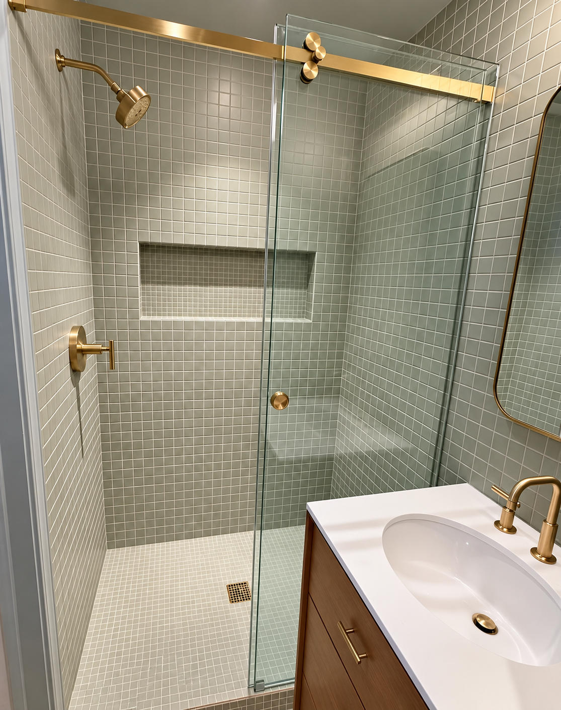 Completed gray mosaic tile shower with brushed brass fixtures and white vanity