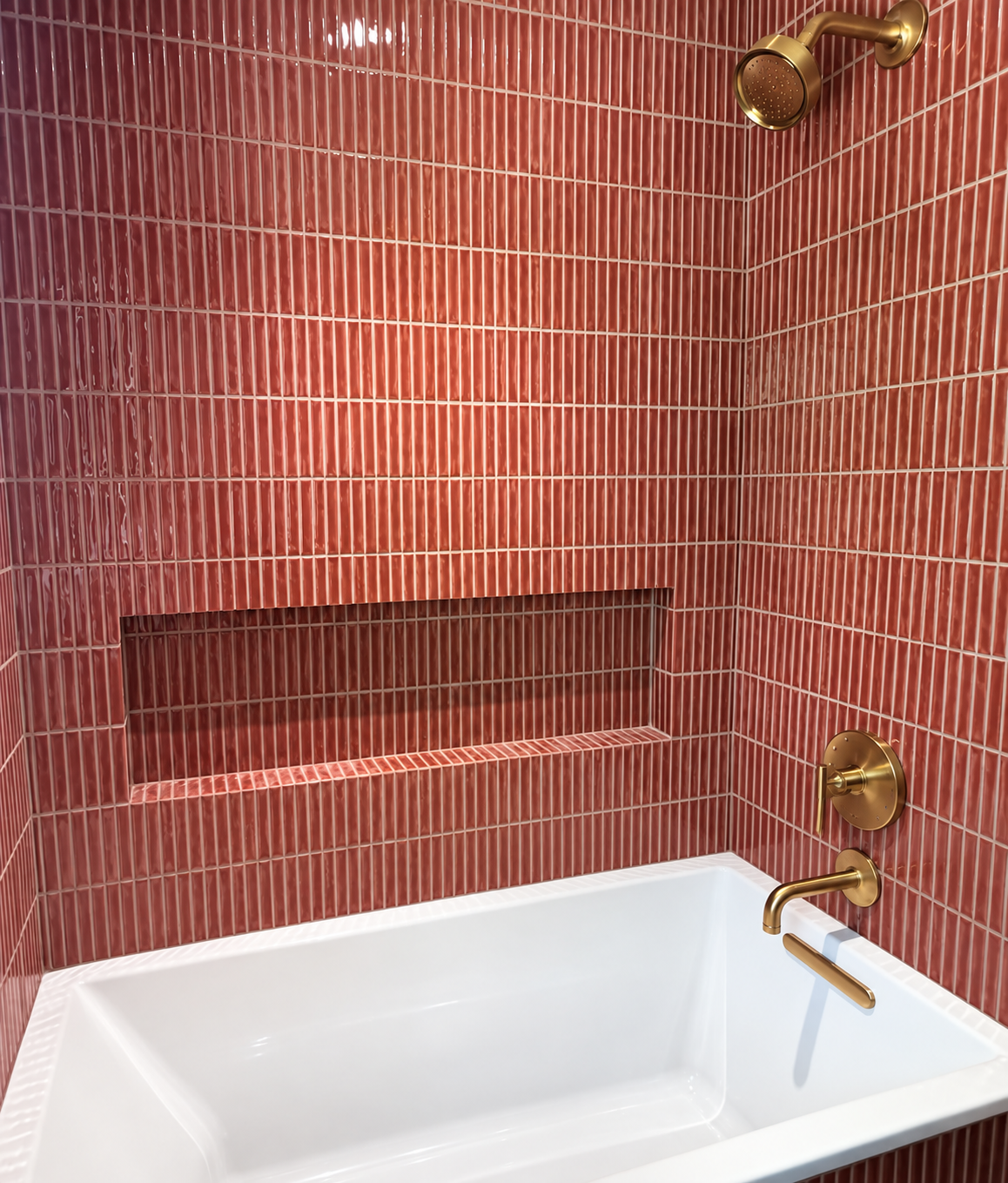 Rose colored narrow tile bathtub surround with brass fixtures