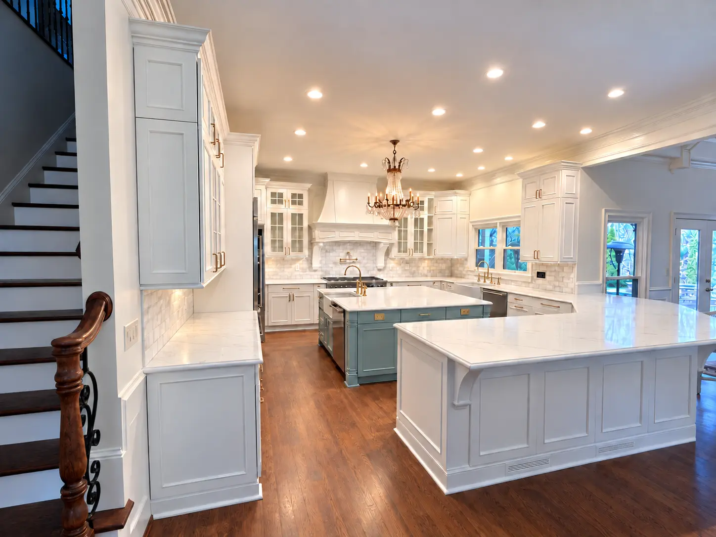 Bright finished kitchen with white cabinets, two islands and wood flooring